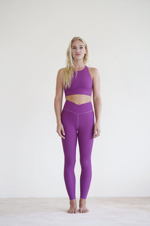 Yogini wearing purple cross waist yoga leggings and purple yoga top 