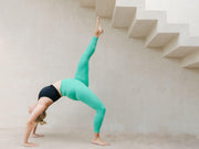Yogini wearing turquoise high waisted yoga leggings and black yoga top