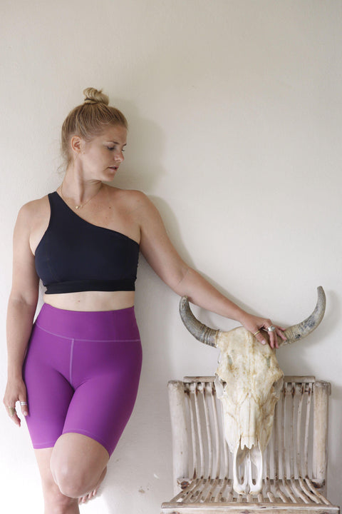 Eva Estlander in one shoulder black yoga top and purple biker shorts by Moonah Wear