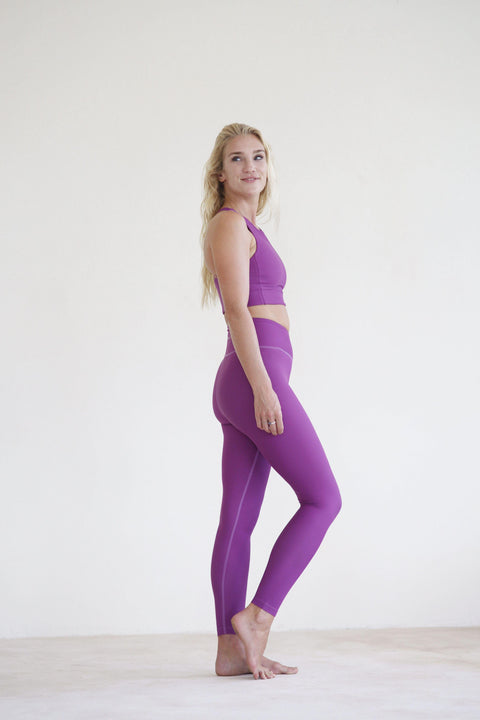 Yoga girl wearing purple high waist yoga leggings and purple yoga top
